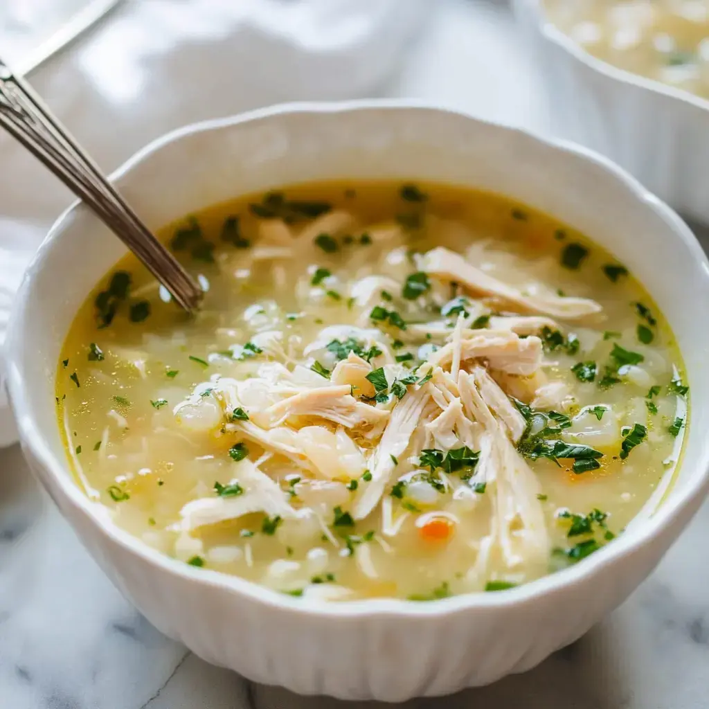 Un bol de soupe au poulet avec du poulet effiloché et du persil haché en garniture.