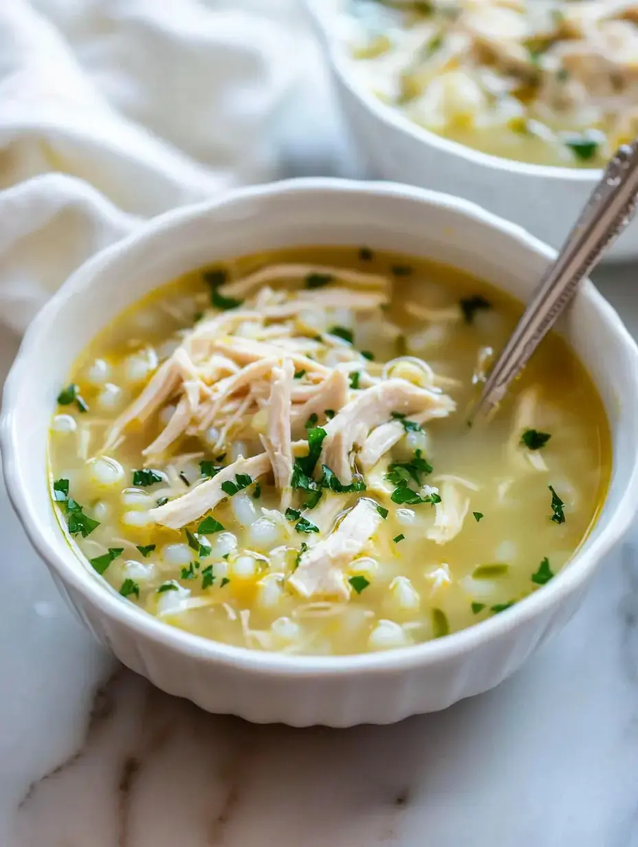 Un bol de soupe au poulet avec du poulet émietté, du maïs et du persil saupoudré dessus.
